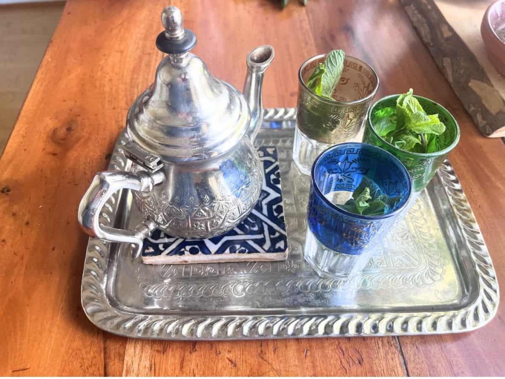 Moroccan tea setting with a brass tea kettle, tea glasses on a tea tray.