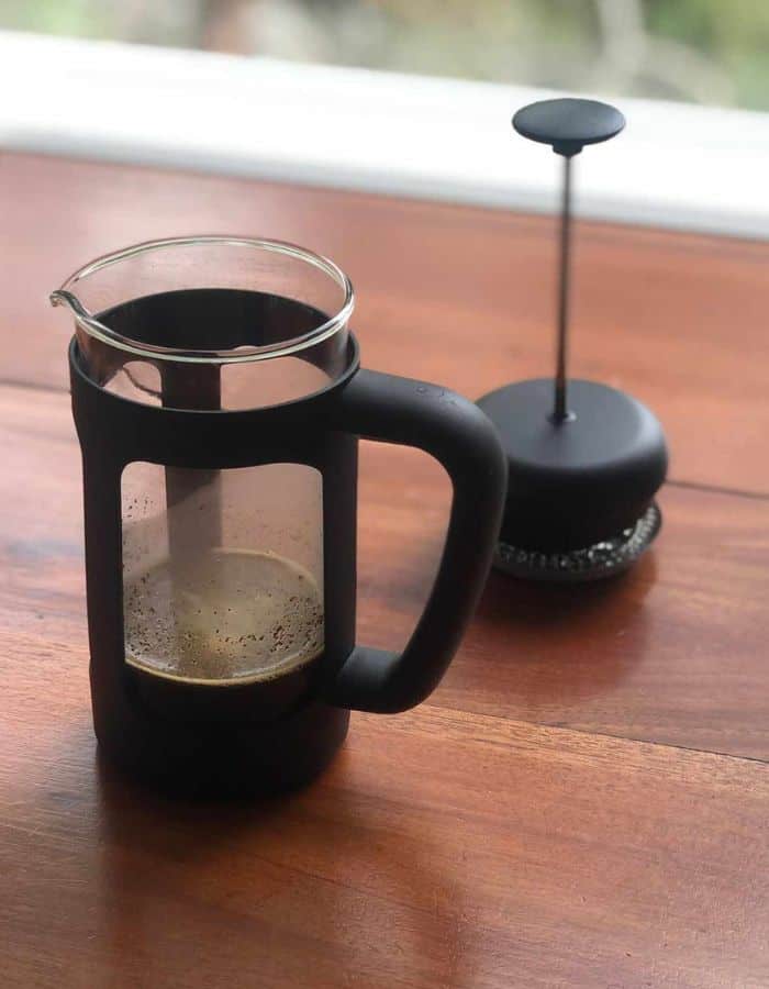 A French press on the table with the plunge separate on the side.