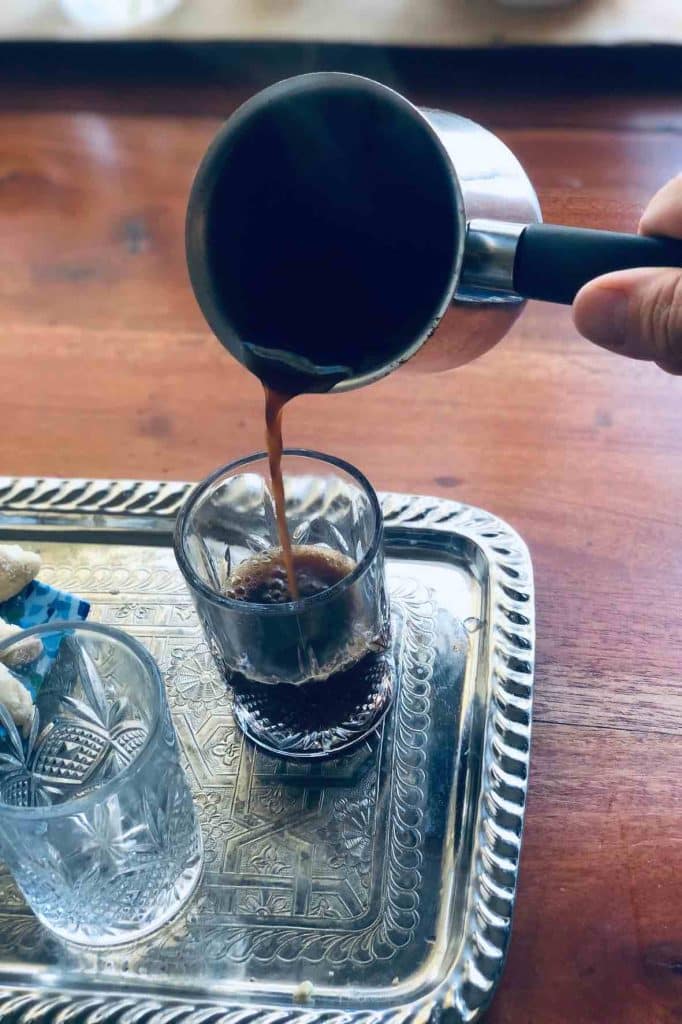 Pouring the spiced Moroccan coffee into the glass on a silver tray.