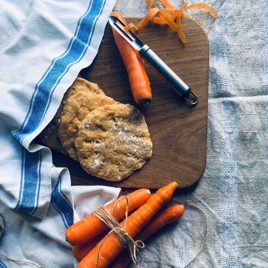 Sourdough flatbread with carrots on a wooden board.