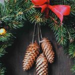 Close up of a Nordic Christmas wreath with spruce branches, pine corn, and red ribbon.