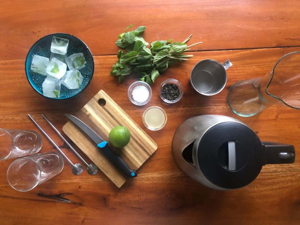Ingredients and tools for making iced Moroccan mint tea.