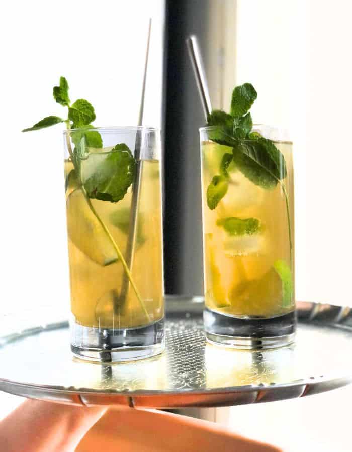 Two glasses of iced mint tea on a silver colored tray.
