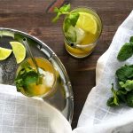 Iced Moroccan mint tea served in the glasses with some lime slices on a silver tray.