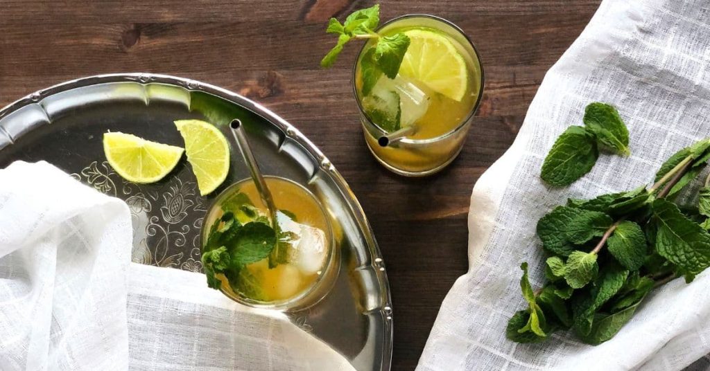 Iced Moroccan Mint Tea is served in tall drink glasses with mint sprigs and lime.