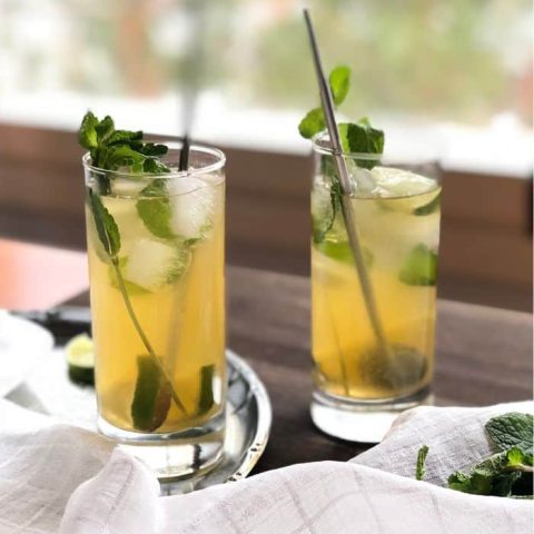 Two highball glasses filled with Iced Moroccan Mint Tea, mint ice glasses and lime slices.