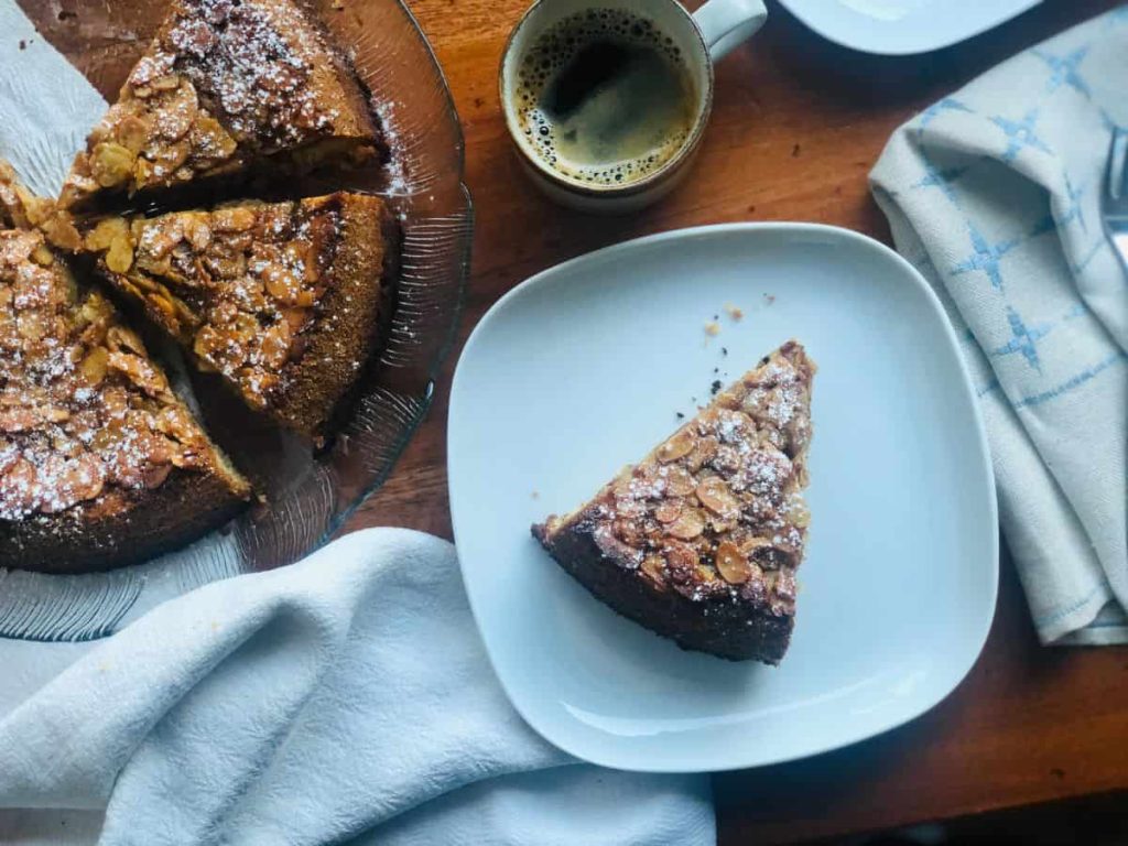 Piece of Tosca cake on a plate with some coffee.