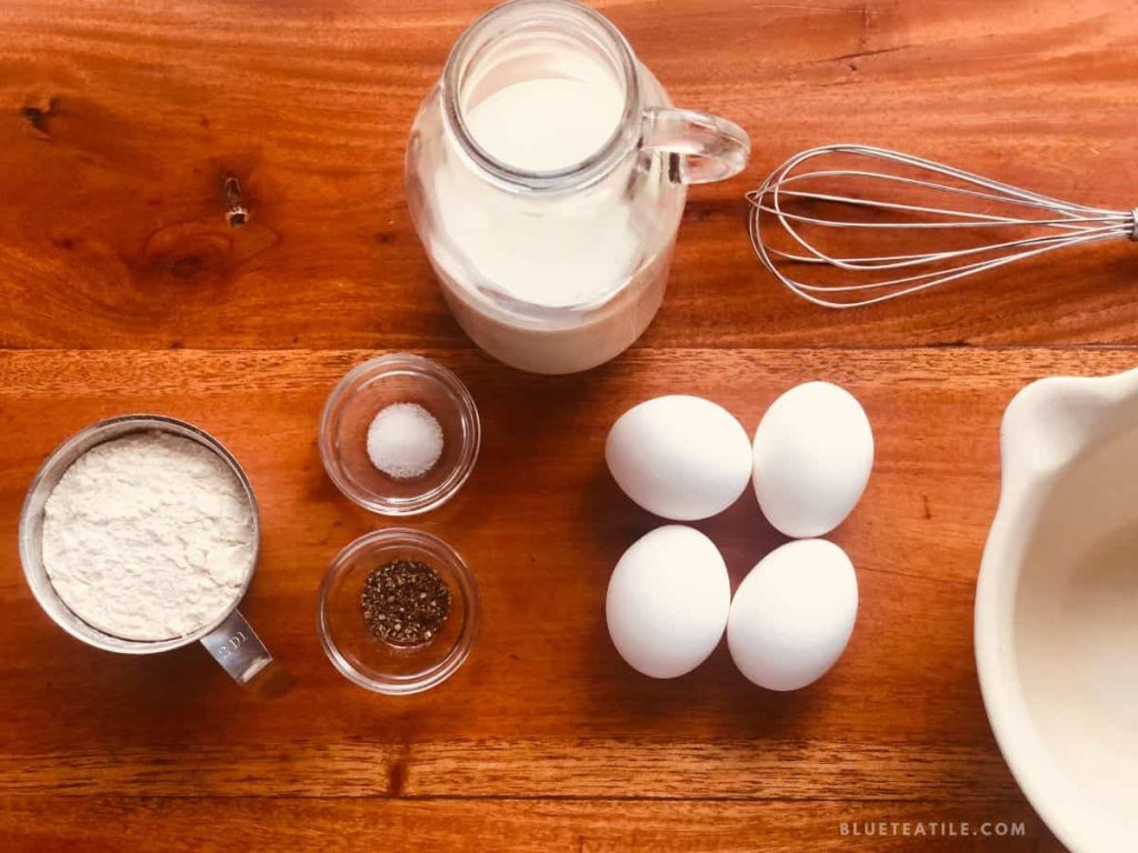 Flat lay of the ingredients needed for the Swedish pancakes: wheat flour, milk, eggs, salt, and cardamom.