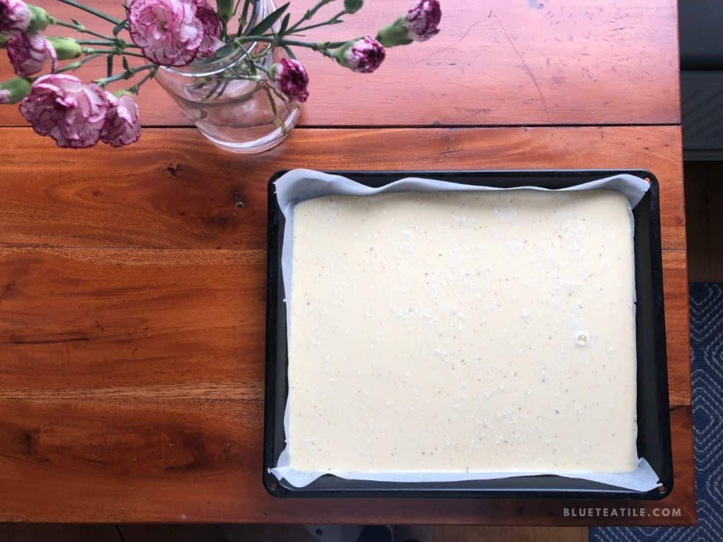 Uncooked pancake batter on a rectangle oven pan lined with parchment paper.