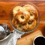 Finnish butter eye buns, voisilmäpulla, on a glass tray with a coffee pot and cup on the wooden table.