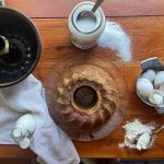 Kefir coffee cake with cinnamon and cardamom, unmolded from the pan with cracked egg shells, sugar, and kefir on the side.