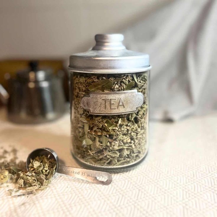 A homemade winter tea mix in a glass jar with a metallic lid.