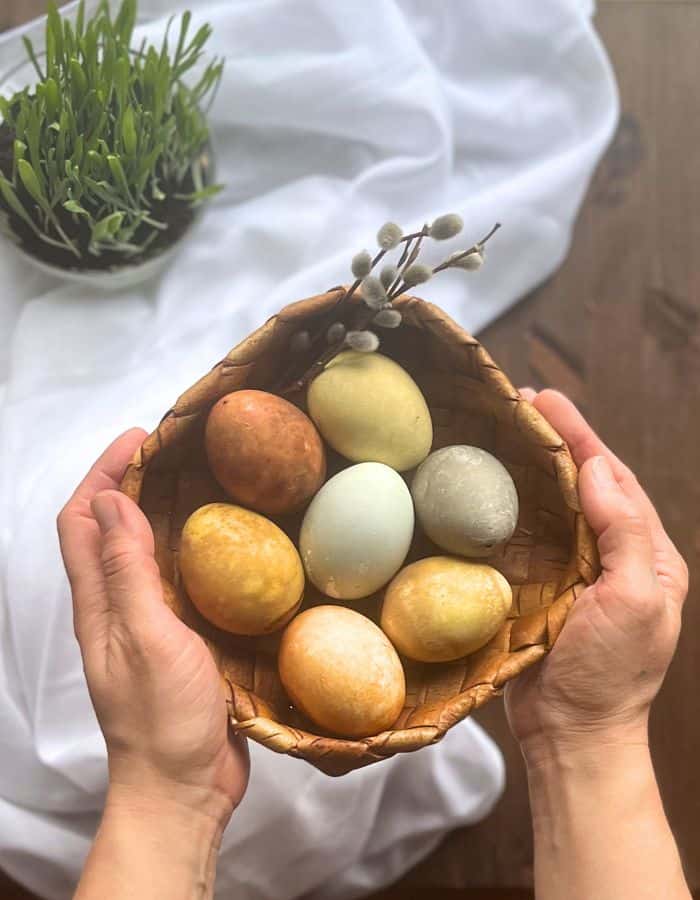 A woman holding an Easter basked filled with naturally dyed eggs.