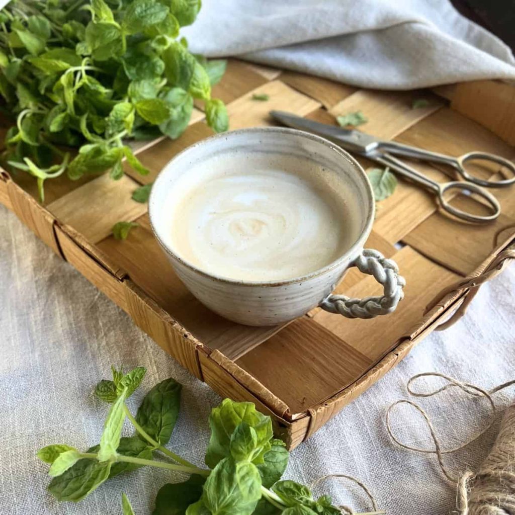 Naturally prepared mint latte with fresh mint leaves on the side.
