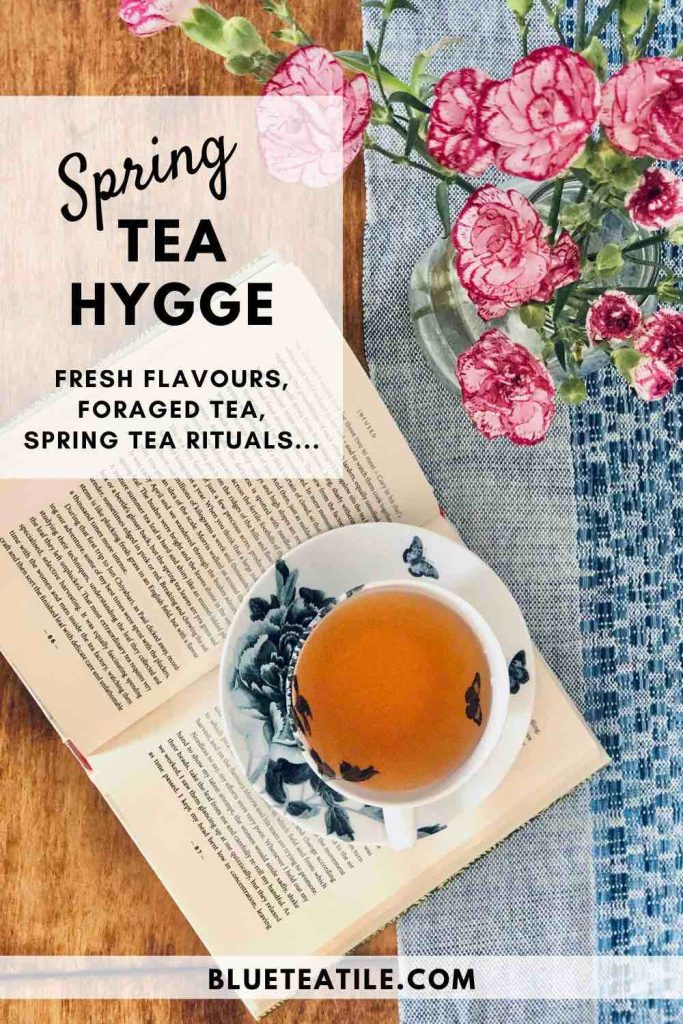Spring tea hygge with a cup of tea, a tea book, and a bouquet of pink spring flowers.