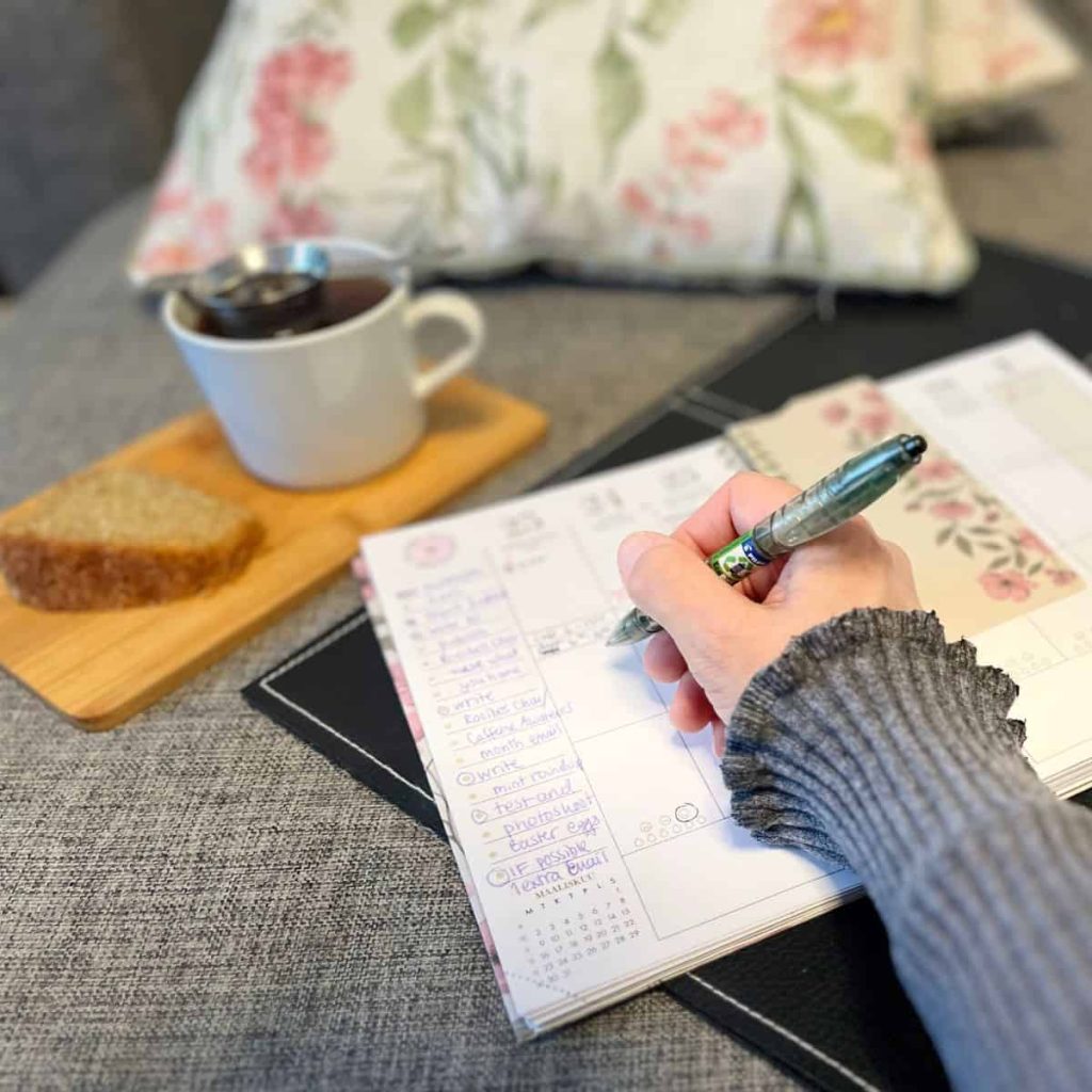 A woman is holding a pen to plan her week in her calendar with flowers.