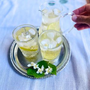 An iced tea tray with jar and two glasses filled with iced jasmine green tea.